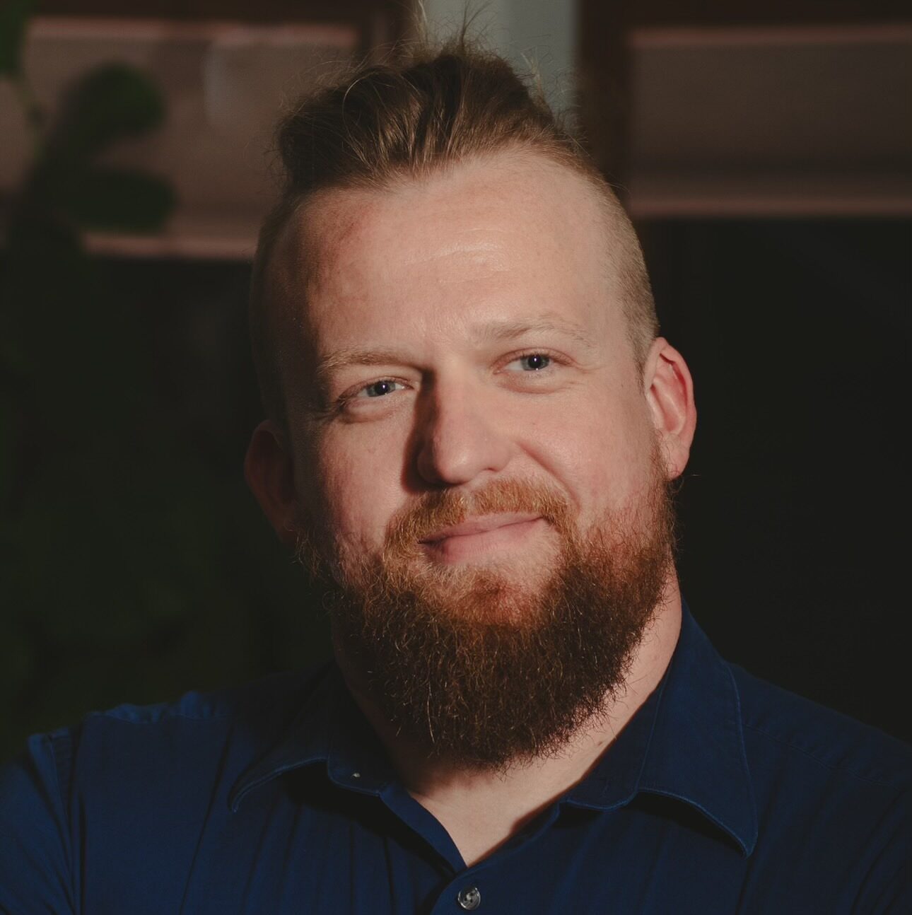 Portrait of Dan smiling with blue background