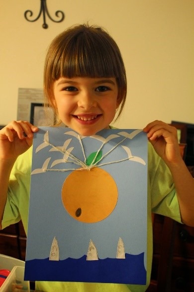 Child holding hand made drawing of a orange